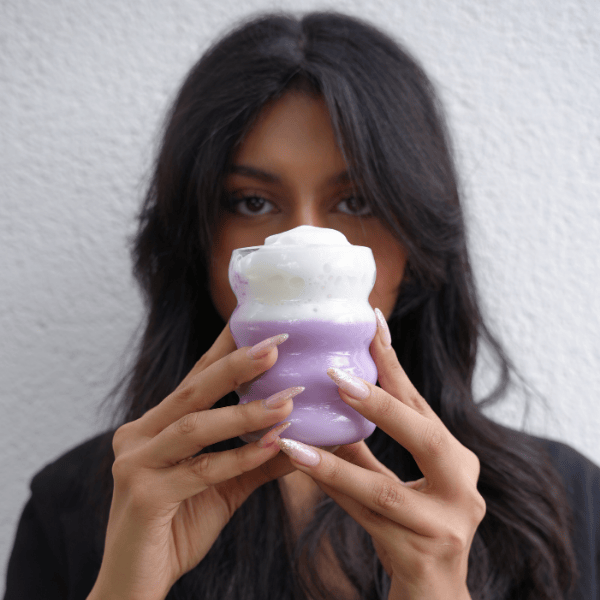 Femme buvant un ube latte violet à la poudre d’ube Ubecious