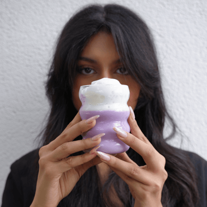 Femme buvant un ube latte violet à la poudre d’ube Ubecious